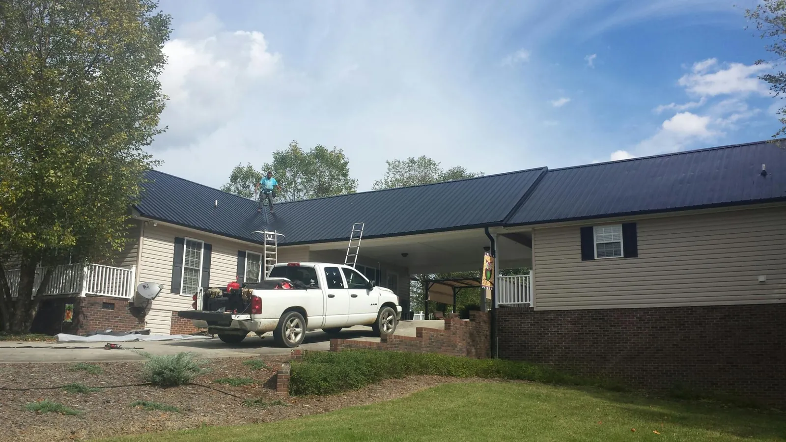 Black metal roof over a home and attached breezeway with ladders set in Ellenton