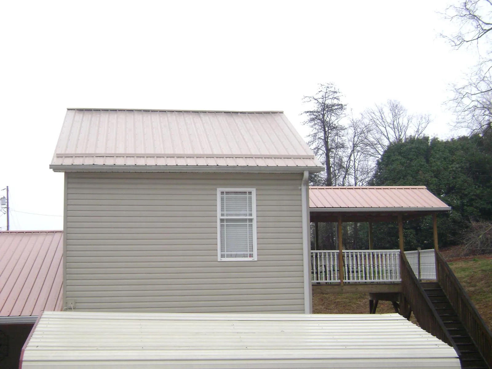 Tan metal roofs on a two story addition and attached porch, from a Roof Replacement job in Ellenton